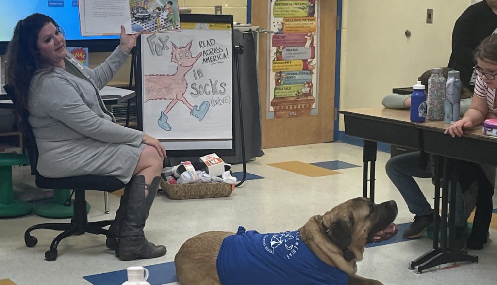 Duncan lying on the floor while Dr. Haines reads a book to the students.

