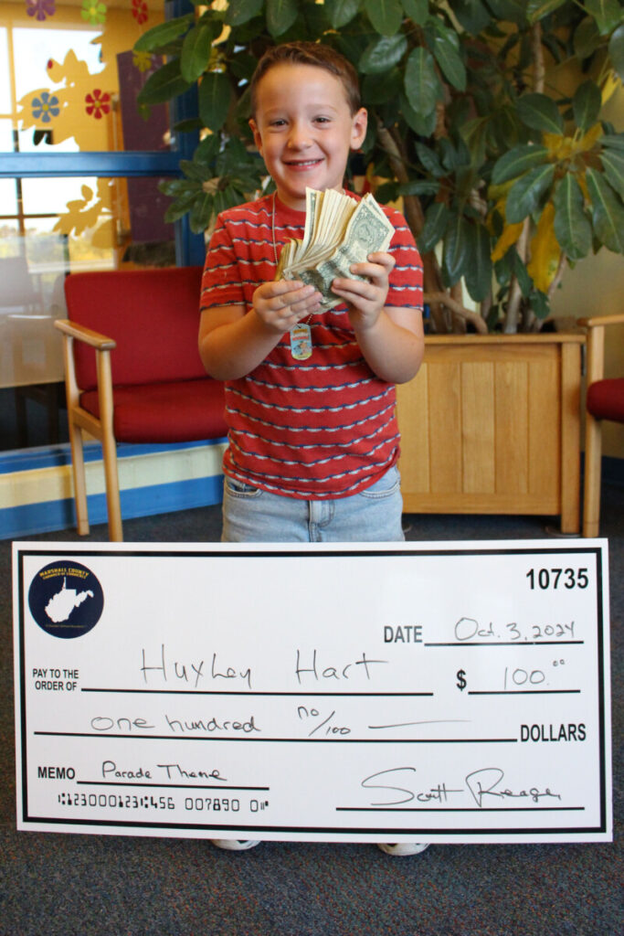 Huxley poses with his oversized check and a bundle of 100, one-dollar bills he won.